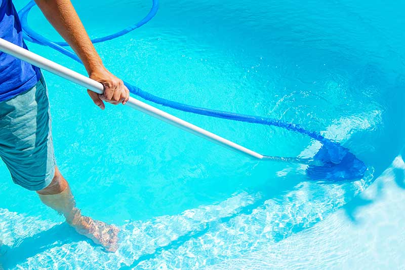 Skimming a clear blue swimming pool