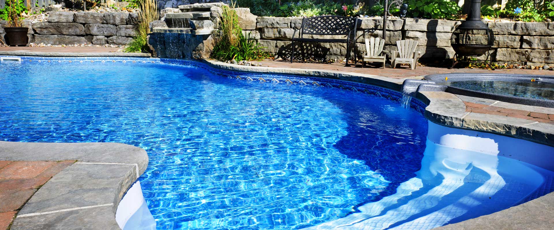 Clear blue pool water flowing into a quiet backyard retreat